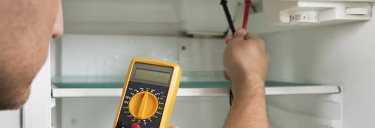 Refrigerator repair technician testing electrical components with a multimeter in Myrtle Beach, SC